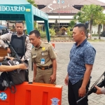Tak mau kecolongan, personil yang bertugas di Samsat Sidoarjo dipersenjatai lengkap. Tampak petugas sedang memeriksa tas pengunjung Samsat.