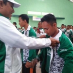 Mirza, Ketua KONI Tuban saat mengenakan jaket kepada atlet.
