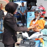 Salah satu Polwan saat membagikan bunga kepada seorang Ibu yang tengah mengurus SIM.