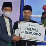 Ketua MUI Gresik, KH Mansoer Sodiq, saat menyerahkan hadiah dan trofi kepada Miftakhul Firman Ferdiansyah Efendi. Foto: SYUHUD/ BANGSAONLINE