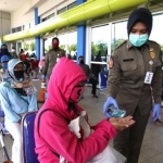 Petugas memberi hand sanitizer kepada pengunjung yang antri belanja di Lumbung Pangan Jatim di Jatim Expo, Selasa (21/4/2020). Foto: ist/bangsaonline.com