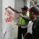 Kapolsek Gresik AKP Suyatmi bersama anggotanya ketika menghapus tulisan G 30 S-PKI di salah satu dinding. foto: SYUHUD/ BANGSAONLINE