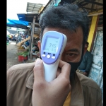 Salah satu pengunjung pasar saat sedang diukur suhu tubuhnya.