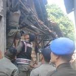 Petugas Satpol PP saat melakukan pemeriksaan di rumah yang diduga kuat masih memproduksi arak dengan menaiki genteng. foto: SUWANDI/ BANGSAONLINE
