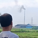 Salah seorang warga RT 01/RW 04, Dusun Ngatup, Desa Kambingan, Kecamatan Pagu, Kabupaten Kediri saat memandangi cerobong asap milik pabrik pupuk organik PT KTS yang diduga menjadi penyebab terjadinya pencemaran udara. foto: MUJI HARJITA/ BANGSAONLINE