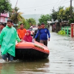 Petugas BPBD saat mengevakuasi warga ke tempat pengungsian menggunakan perahu karet.