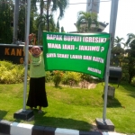 Nashiro memasang spanduk berisi tagih janji di depan Kantor Pemkab Gresik (foto: ist)