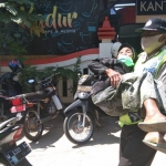 Aiptu Gatot Irianto saat menggendong nenek yang mau mengambil BST di kantor pos