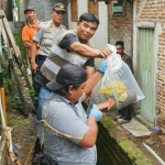 Petugas menunjukkan jasad bayi usai dibongkar dari kuburannya di samping rumah seorang janda muda.