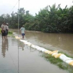 Warga gotong royong memasang sandbag untuk mencegah luberan air meluas.