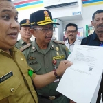 Pejabat DPM-PTSP Kota Malang R Dangdung Julhariyanto disaksikan Kasatpol PP Kota Malang Priyadi, menyampaikan pemberitahuan perihal persyaratan dan pelanggaran yang ada di toko modern Indomaret di Sukun, Selasa (23/07). foto: IWAN IRAWAN/ BANGSAONLINE