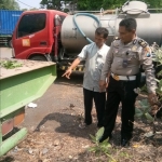 Petugas sedang menunjuk truk bermuatan beton.
