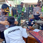 Kapolres Pasuruan, AKBP Rofiq Ripto Himawan saat memakaikan masker kepada salah satu pengendara motor yang kedapatan tidak mengenakan masker di Simpang 3 Pasar Bangil. (foto: ANDY F/ BANGSAONLINE)