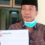 Hosyan Muhammad menunjukkan hasil swab/PCR dari Hospital Siloam Surabaya saat konferensi pers di gedung DPRD Bangkalan, Kamis (30/4).