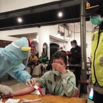 Salah satu pengunjung cafe menutup mata saat petugas mengambil sampel darah untuk dilakukan rapid test.