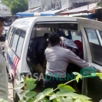 Polisi dibantu warga saat hendak memasukkan jenazah ke ambulans.
foto: GUNAWAN/ BANGSAONLINE