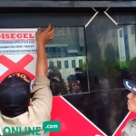 Petugas Satpol PP memasang stiker segel di pintu masuk tempat karaoke Maxi Brilian.