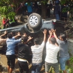 Warga saat melakukan evakuasi tubuh korban yang ditimpa Avanza. Foto: SOFFAN S/BANGSAONLINE
