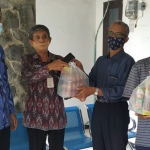 Petugas saat menyerahkan bantuan sembako kepada warga yang sedang menjalani isolasi mandiri. (foto: ist)