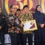 Gus Azmi  saat menerima penghargaan didampingi Kepala Badan Pengembangan Sumber Daya Manusia (BPSDM) Pemerintah Provinsi Jawa Timur Dr Ramliyanto, SP, MP dan didampingi Direktur Indonesia Achivement Center Fitria Widistuti di Hotel Mercure Surabaya, Jumat (24/4/2026) malam. Foto: MMA/bangsaonline