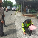 Petugas kepolisian saat olah TKP kecelakaan adu banteng yang melibatkan dua pemotor di Jalan Raya Masangan Wetan, Sidoarjo.