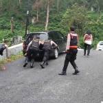 Tim Satgas Ganjal Ban Polres Magetan mendorong mobil wisatawan yang tak kuat nanjak.