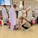 Salah satu petugas saat memberikan sendal bagi jemaah pria yang masih kenakan sepatu saat ihram.
