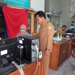 Kades Lowayu, Amin Iskandar mengecek perangkatnya tengah melayani pembuatan Adminduk.