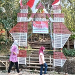 Seorang ibu sedang berolahraga melintas dengan anaknya di depan jalur pendakian ke puncak Gunung Klotok yang diberi garis polisi. (foto: MUJI HARJITA/ BANGSAONLINE)