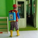 Seorang petugas dari PMI Tuban sedang menyemprot ruangan pesantren. 