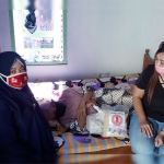 Koordinator Relawan Gotong Royong Kediri, Irma Yulianti, saat menyerahkan bantuan secara simbolis kepada Ketua PDKK, Umi Salamah yang menerima dengan rebahan. foto: MUJI HARJITA/ BANGSAONLINE