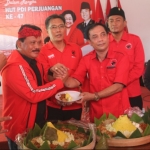 ?Ketua DPC PDI Perjuangan Nganjuk Tatit Heru Tjahyono menyerahkan potongan tumpeng ke Wakil Bupati Nganjuk Marhaen Jumadi. foto: bambang dj/HARIAN BANGSA.