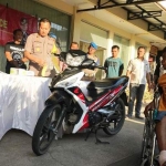 Tersangka duduk di kursi roda dengan barang bukti berupa motor honda Supra X saat dirilis.