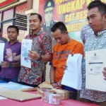 Tersangka berikut barang bukti berupa uang dan surat-surat saat dirilis.