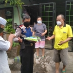 Salah satu aparat polisi sedang membagikan beras per orang 5 kg  dan uang Rp 50 ribu sedekah dari Kiai Asep Saifuddin Chalim, kepada warga Siwalankerto Utara Surabaya, Jumat (22/5/2020). foto: MMA/ BANGSAONLINE.COM