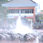 Personel Polres Gresik yang naik pangkat ketika disiram air dengan mobil water cannon. Foto: Ist