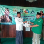 H. Syafiuddin Asmoro menyerahkan secara simbolis bantuan sembako kepada Ketua GP Ansor H. Hasani Zubair.