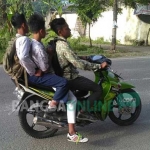 Tampak pelajar tak mengenakan helm dan boncengan tiga. foto: AHMAD/ BANGSAONLINE