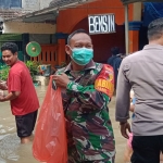 Babinsa Koramil 0817/01 Driyorejo, Serma Rudianto, saat membantu warga terdampak banjir.