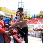 Kapolres Kediri AKBP Roni Saiful Faton saat memakaikan helm pada para pengguna jalan. foto: ARIF KURNIAWAN/ BANGSAONLINE