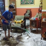 Pemilik rumah di Kelurahan Sisir bergotong royong membersihkan rumahnya yang terendam banjir. 