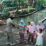 Petugas Satpol PP Kota Kediri saar membagikan masker gratis kepada pengunjung tempat wisata Sumber Banteng, sebelum mereka meninggalkan tempat. (foto: ist.)