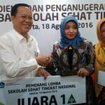 Ketua TP PKK Kabupaten Gresik, Hj. Maria Ulfa Sambari menerima piala dari Dirjen Pendidikan Dasar dan Menengah, Hamid Muhammad. foto: SYUHUD/ BANGSAONLINE