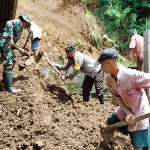 Petugas gabungan bersama warga membantu keluarga Slamet membersihkan material longsor dari rumahnya.