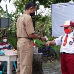 Salah seorang murid SD sedang dicek suhu tubuhnya dengan menggunakan thermogun sebelum masuk kelas oleh guru. foto: ist.