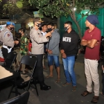 Kapolres Kediri, AKBP Lukman Cahyono saat memakaikan masker kepada warga yang terjaring operasi yustisi. (foto: ist).