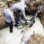 Petugas kepolisian saat mengevakuasi tubuh korban. foto: AKINA/ BANGSAONLINE