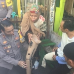 Kapolsek Simokerto Kompol Dwi Nugroho saat memasangkan kaki palsu kepada salah satu penyandang disabilitas.