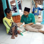 Sudiono Fauzan saat menyalurkan sembako kepada salah satu lansia warga Kecamatan Lekok.