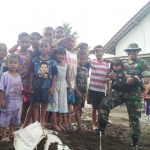 Satgas TMMD ke-104 Jember sedang foto bersama anak-anak Desa Gunung Malang.